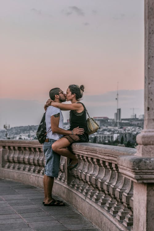 Selective Focus Photography of Man and Woman Kissing on Railings