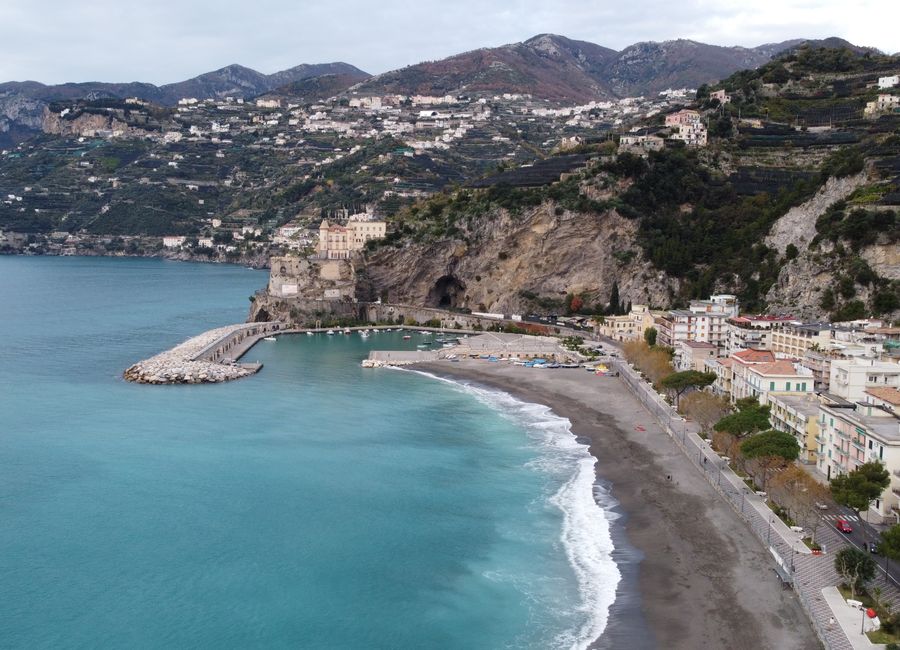 Aerial shot of Sorrento's coastline in Italy with a picturesque beach, bay, and cliffs.