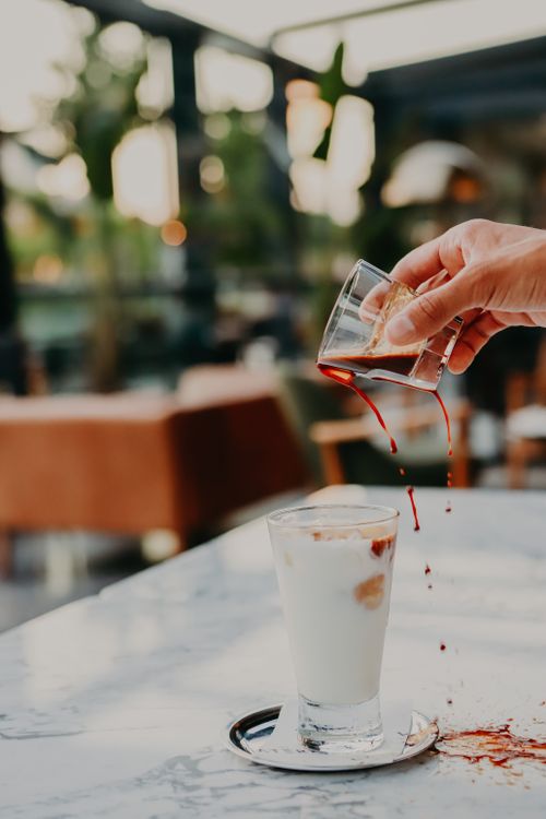 Free Hand pouring espresso over iced milk in a cafe, creating a beautiful layered coffee drink. Stock Photo