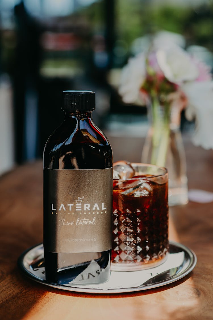 Elegant Bottle With Brown Liquor And Bouquet On Table