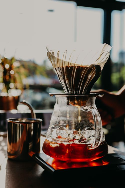 Free A stylish pour-over coffee setup with a glass pitcher and dripper in a sunlit cafe setting. Stock Photo