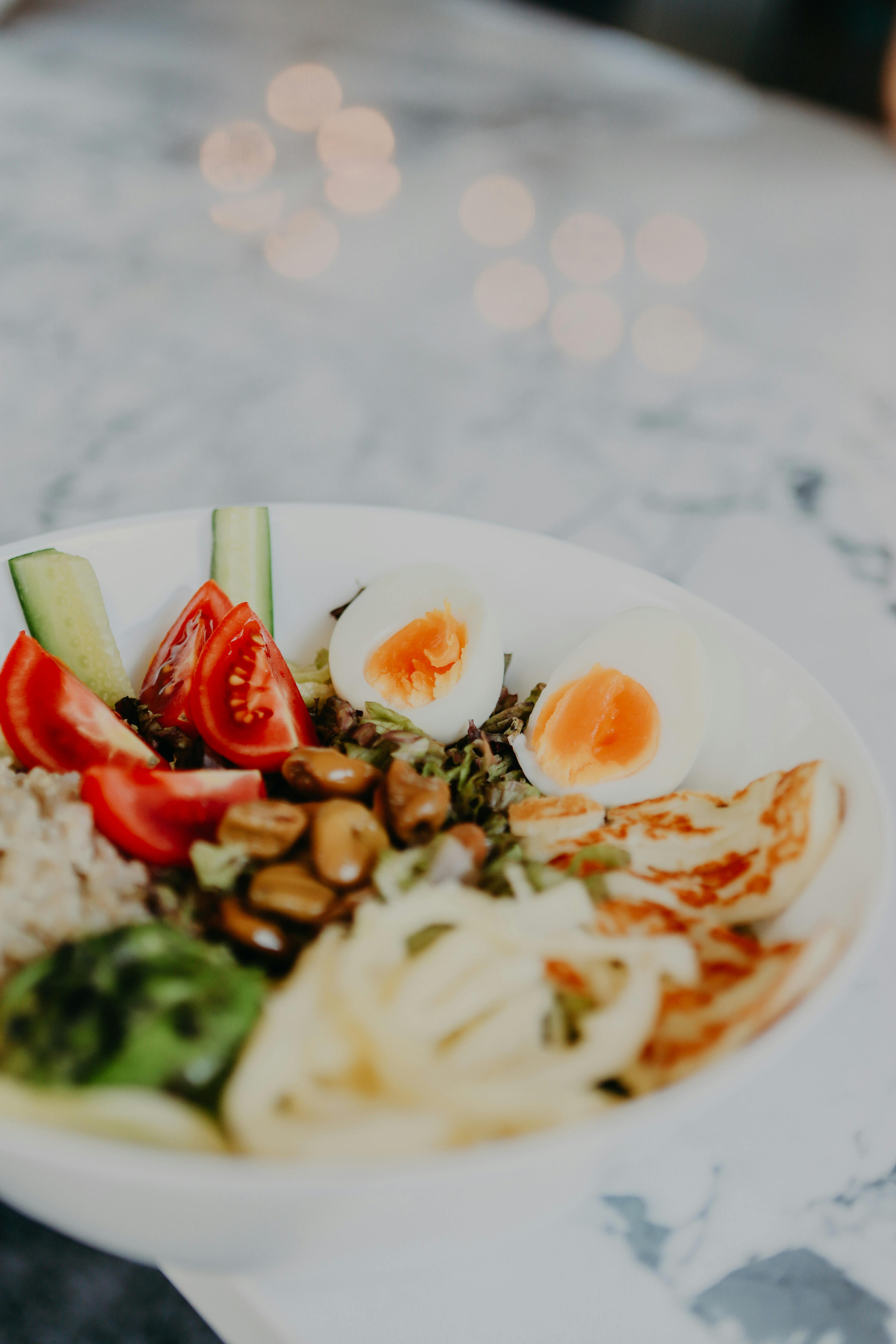 Vibrant bowl featuring eggs, veggies, and grains on a marble surface.