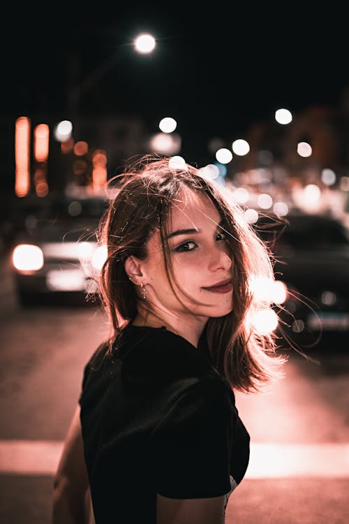 Woman in Black Shirt Standing on Street During Night Time