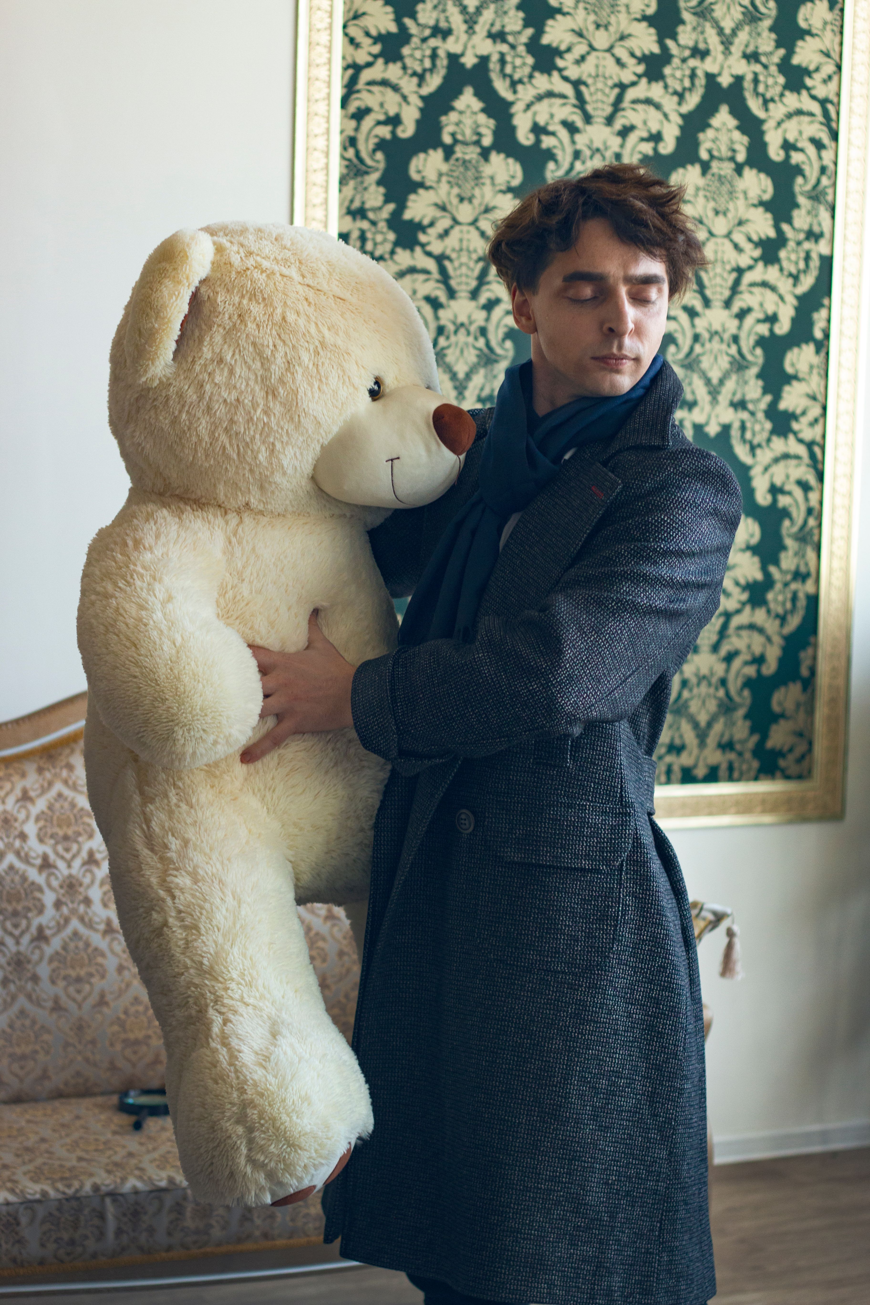 Man with eyes closed hugging large plush toy indoors.