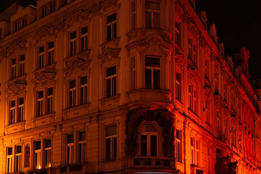 Baroque building exterior illuminated in warm orange hues at nighttime.
