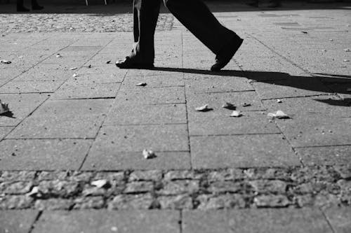 Person Walking on Stone Paved Sidewalk