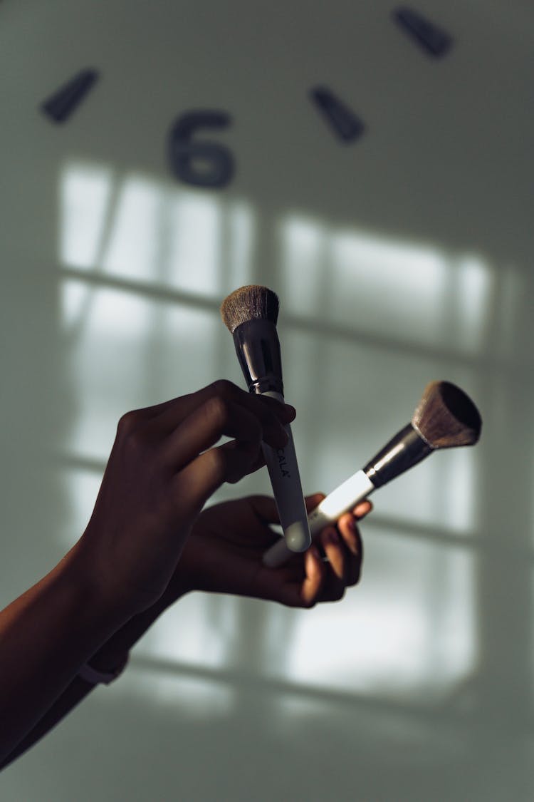 A Person Holding Makeup Brushes 