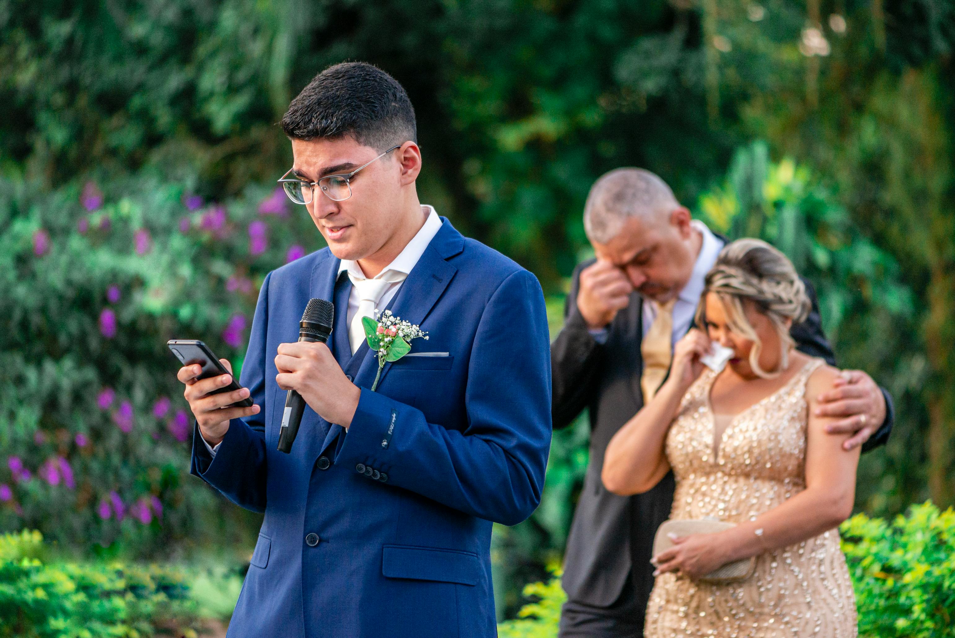 A young man gives a heartfelt speech at an outdoor wedding ceremony.