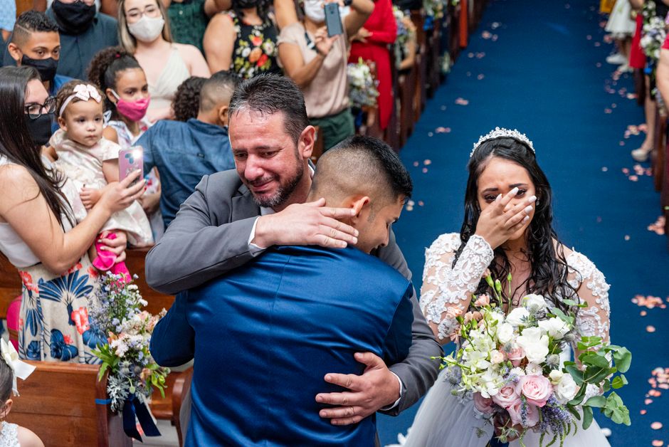 A bride and groom share an emotional moment with family during a church wedding.