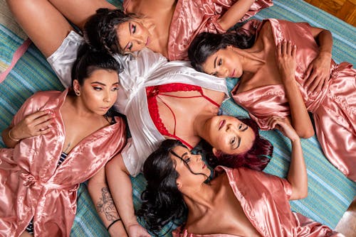 Women Wearing Nightdresses Lying Down on a Floor Together 