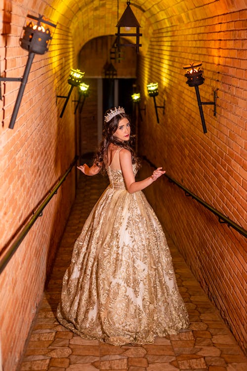 A Woman Wearing a Gown and a Tiara Walking on the Cobblestone Floor of the Walkway