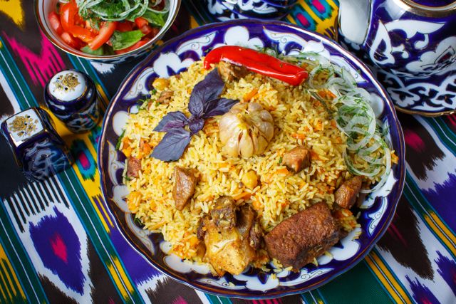 Delicious traditional Kazakh plov served on an artistic plate with vegetables and herbs.