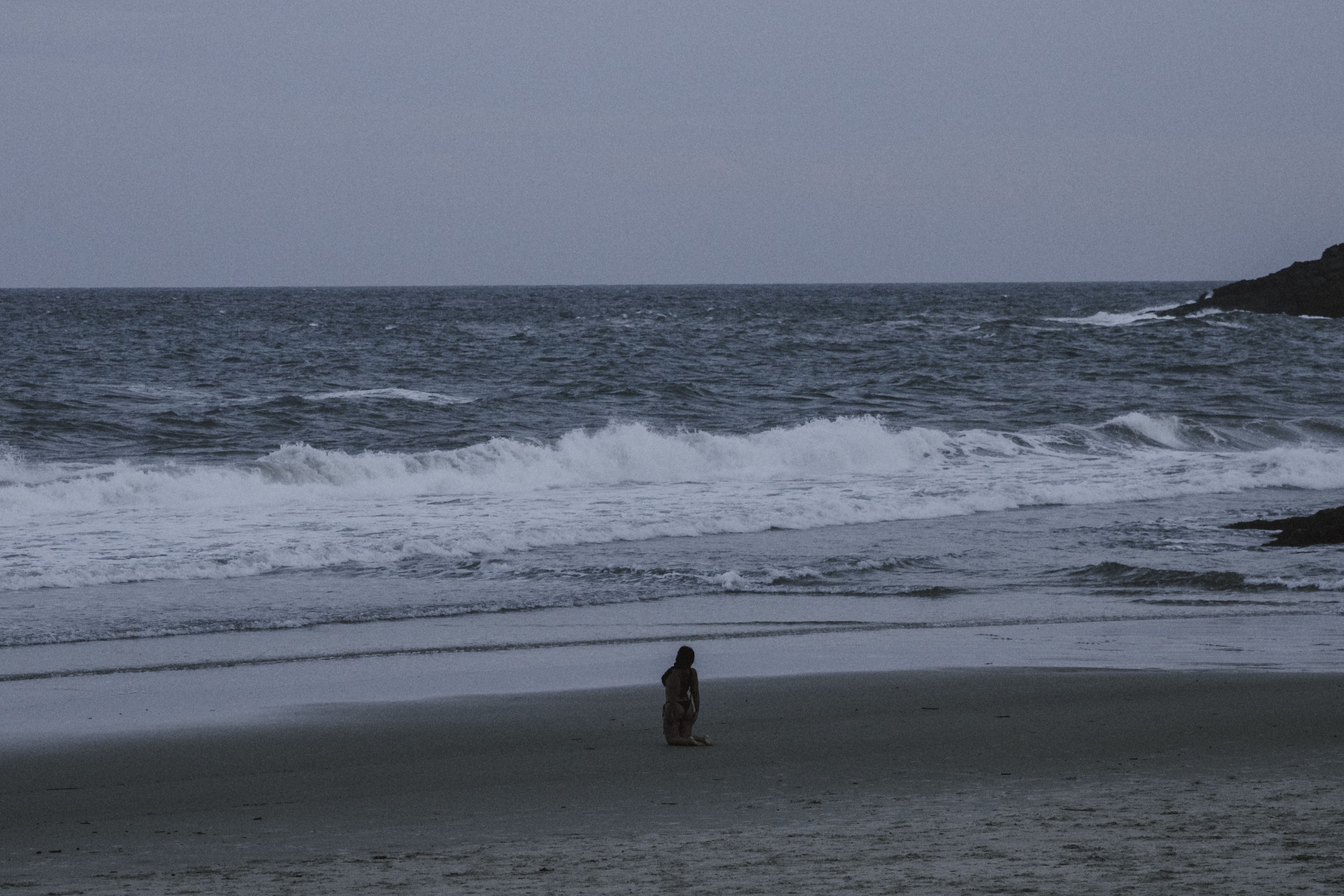 A lone person meditates on Itacaré beach, capturing a serene evening seascape. A lone person meditates on Itacaré beach, capturing a serene evening seascape.