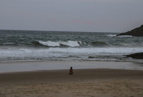 Woman in Bikini Kneeling on Seashore