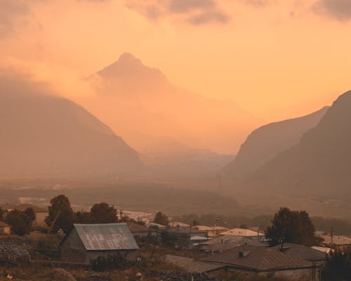 Houses Near Mountains on a Foggy Morning