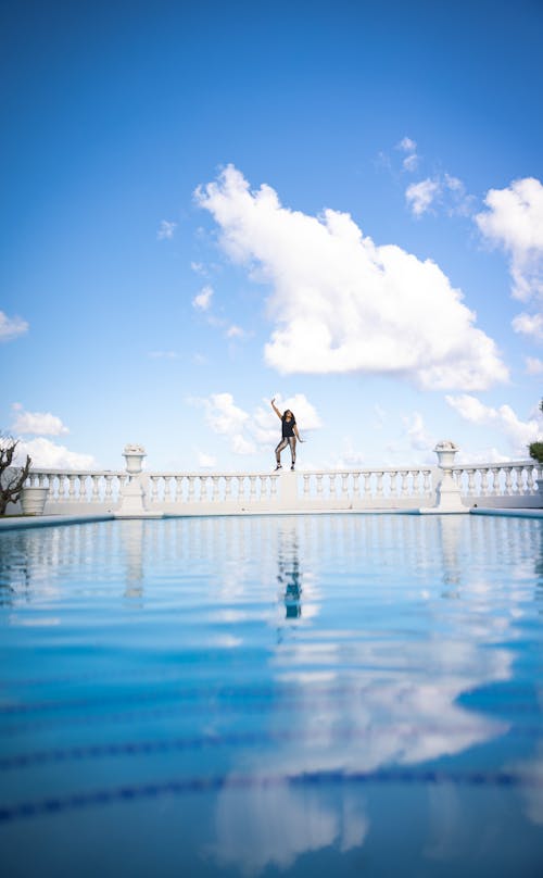 Free A Woman Standing on the Baluster Near the Swimming Pool Stock Photo