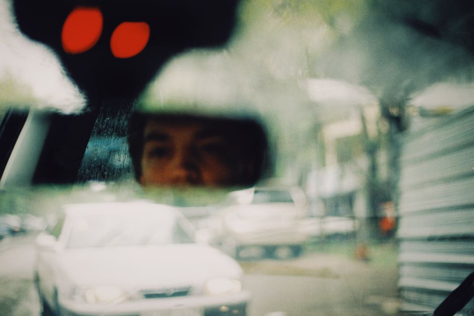 Artistic view of a driver's reflection in a rearview mirror with blurred motion.