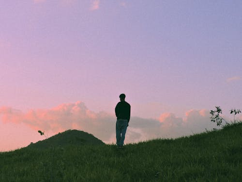 A Man Standing on the Green Hill