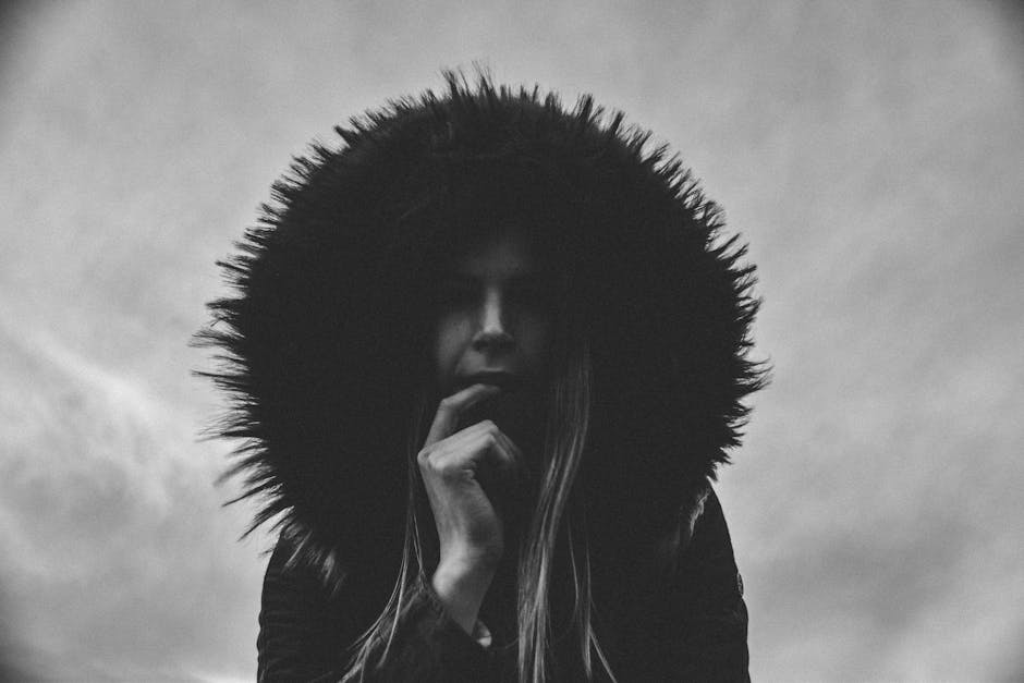 A dramatic black and white portrait of a woman in a fur hood outdoors.