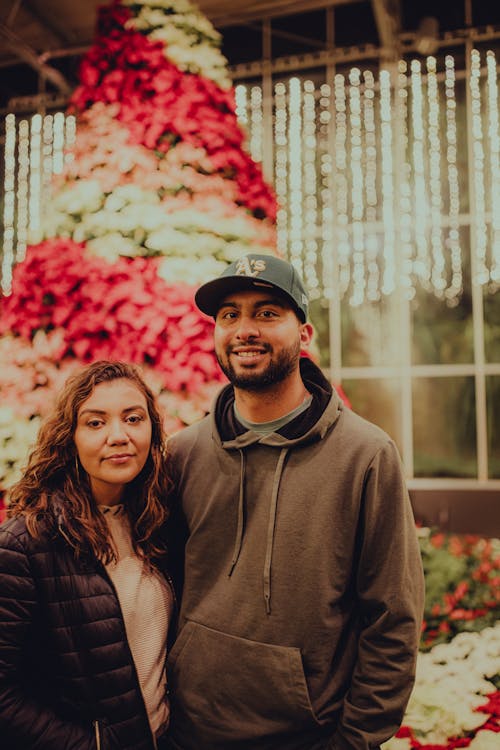 Couple Posing Together Against Christmas Tree