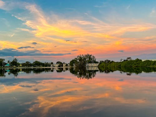 Free Houses and Trees Beside Body of Water During Sunset Stock Photo