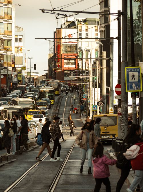 Free A lively city street filled with pedestrians, cars, and trams, showcasing vibrant urban life. Stock Photo