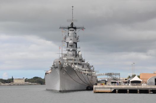 The iconic USS Missouri battleship docked at Pearl Harbor under a cloudy sky, Hawaii.