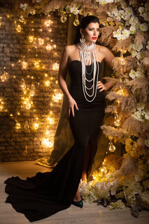 Woman in Black Strapless Long Dress Standing Beside Brown Tree with Lights