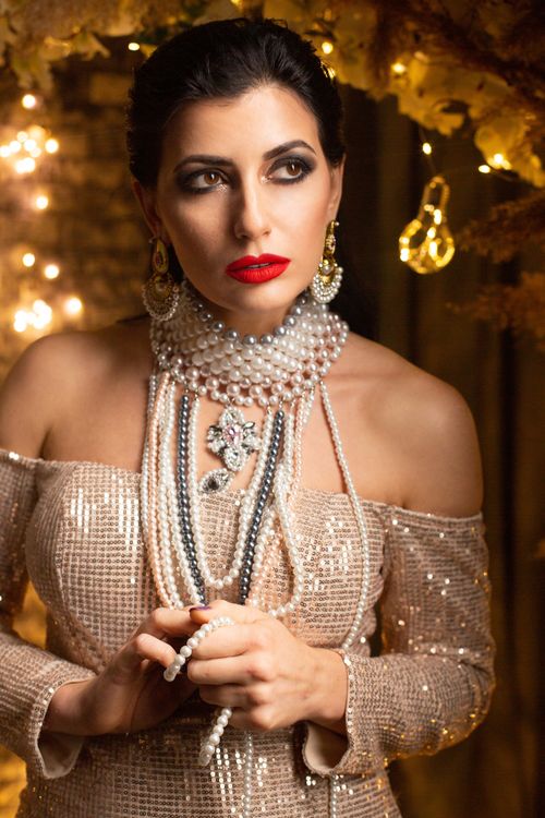 Free A sophisticated woman wearing pearl jewelry and red lipstick, embodying glamour and elegance. Stock Photo