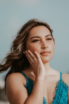 A serene portrait of a woman in a blue dress gazing thoughtfully outdoors.