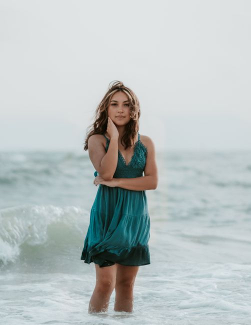 A serene portrait of a young woman standing in the ocean waves, embodying tranquility and natural beauty.