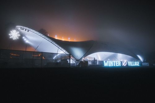 Free A glowing winter village tent with lights and snowflake decor at night, showcasing a festive ambiance. Stock Photo
