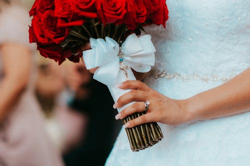 A Close-up of Brides Hand With Wedding Ring and Holding a Bunch of Flowers 