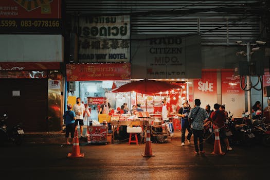 Illuminated street market stall at night with bustling urban atmosphere and colorful signage.