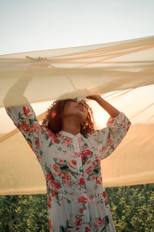 Woman Standing in Flower Field Under See-Through Fabric