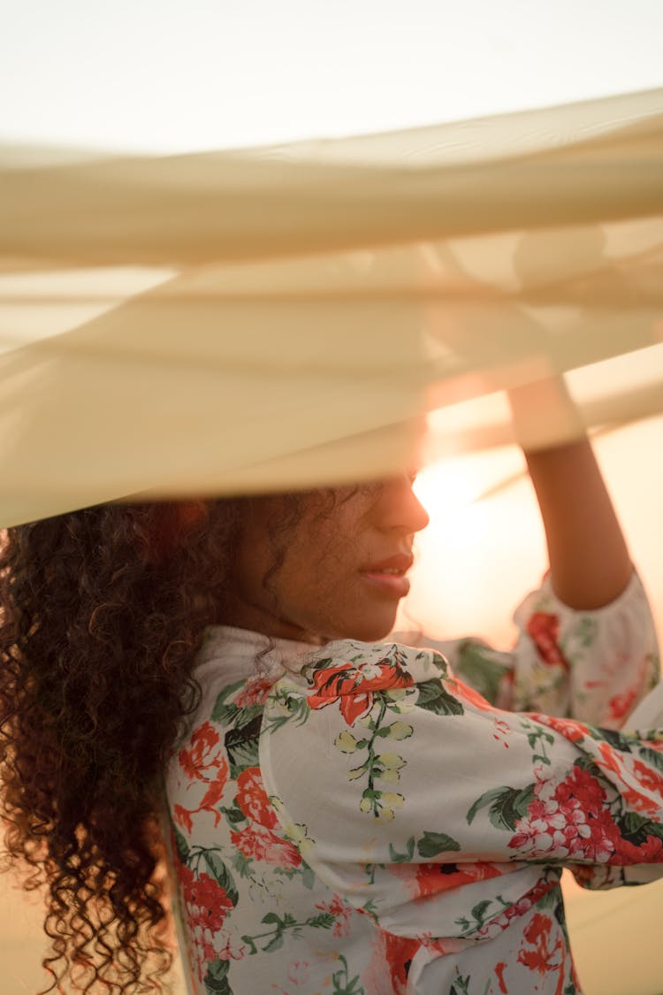 Portrait Of Woman Standing Under Yellow Fabric At Sunset