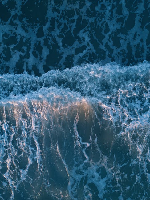 Breathtaking aerial view of crashing ocean waves at sunset, showcasing nature's beauty.