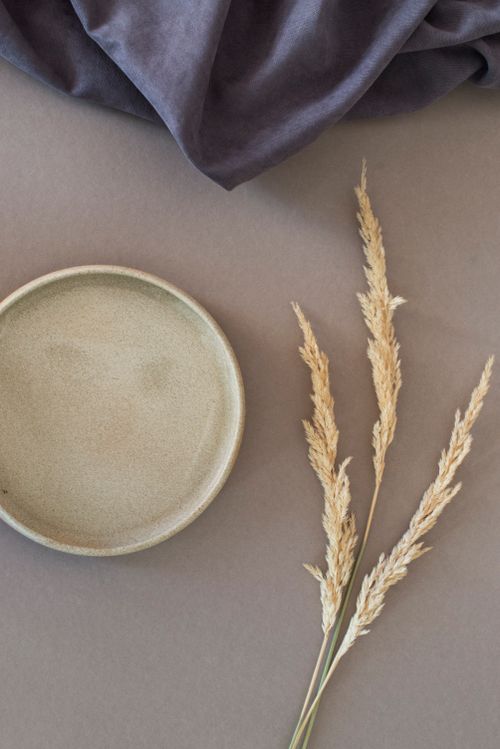 Free A minimalist flat lay with dry grass and a ceramic plate on a textured surface. Stock Photo