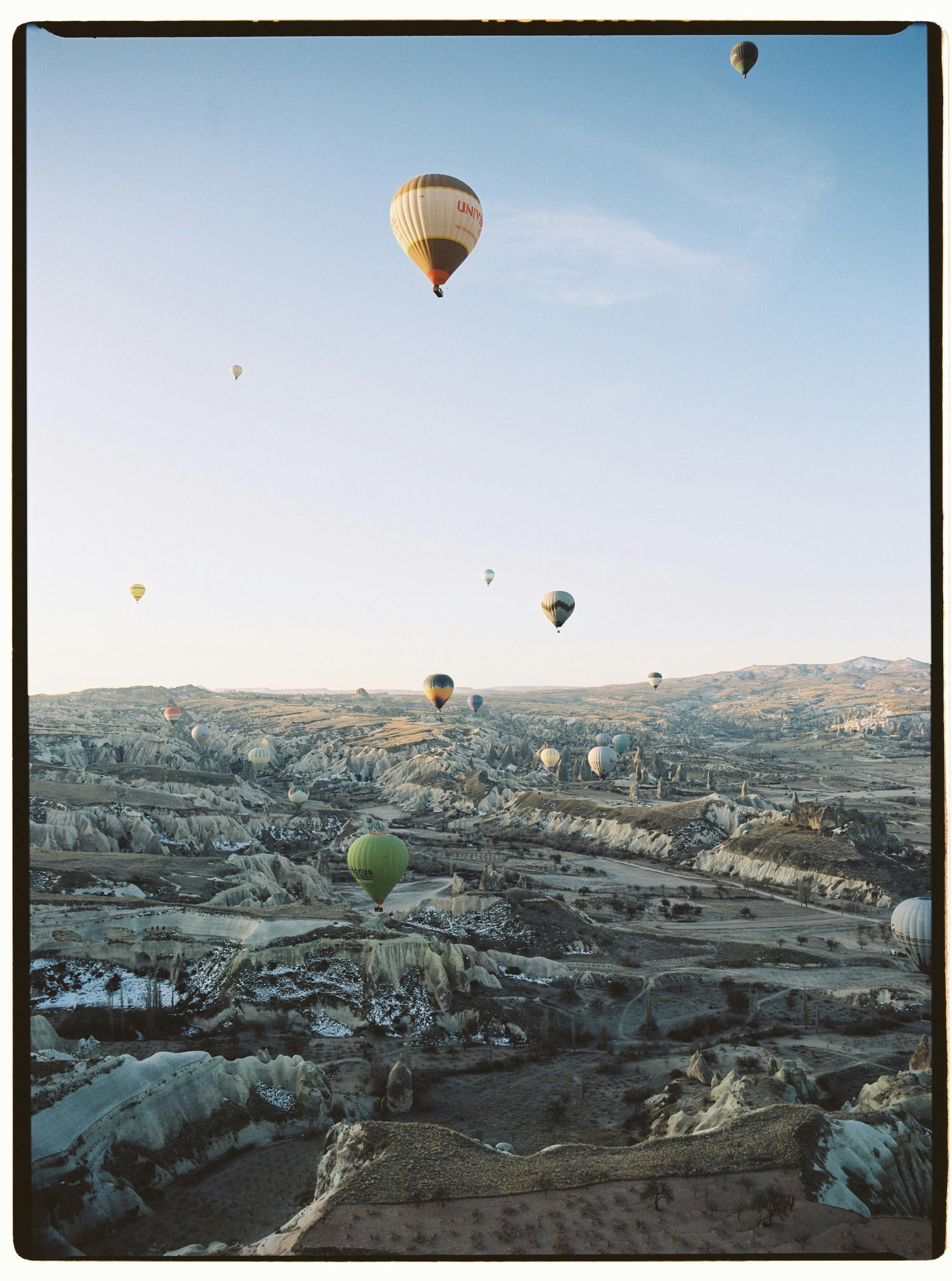 A breathtaking aerial view of hot air balloons soaring over Cappadocia's unique landscape at sunrise.