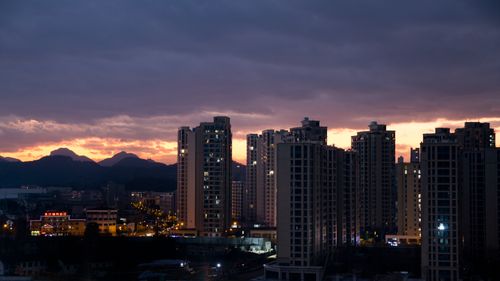 Free A stunning cityscape of high-rise buildings at dusk under a dramatic sky with colorful clouds. Stock Photo