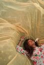 Woman Laying on Tulle Outspread in Meadow and Enjoying Flower Smell