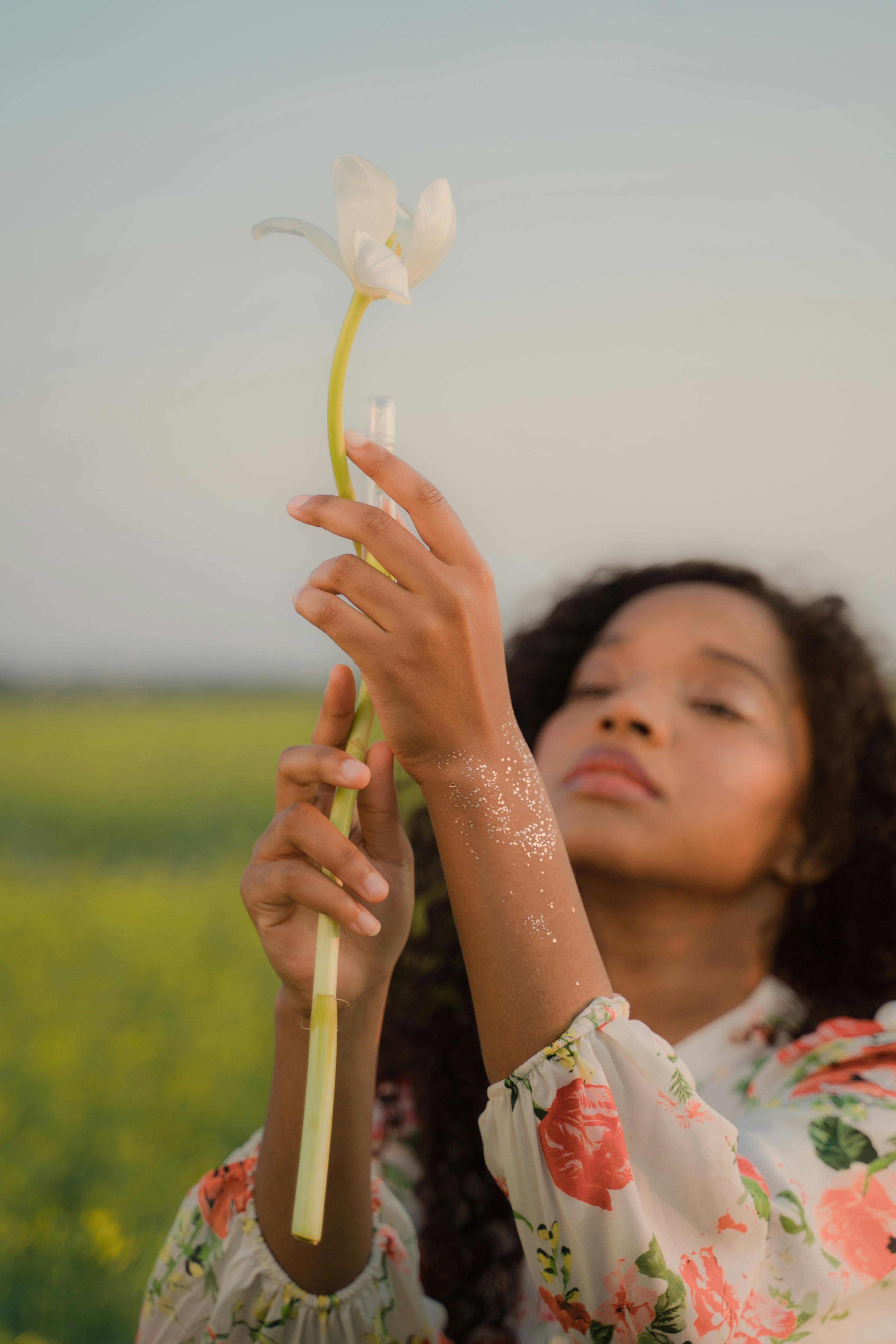 young woman holding white flower with long stem and testing tube