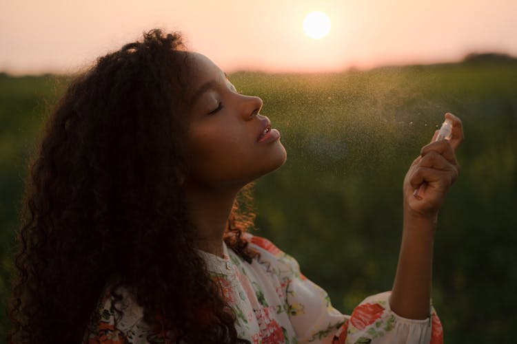 Young Woman Spraying Perfumes Onto Her Face 