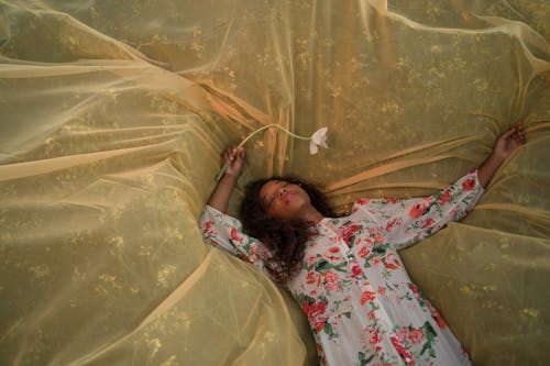 Young Woman Laying on Yellow Tulle Outspread on Meadow