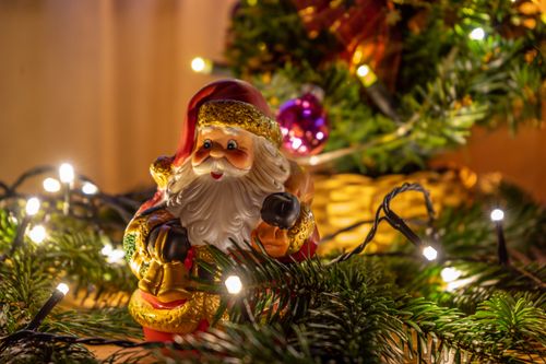 Free Close-up of a Santa Claus figurine surrounded by Christmas lights and festive decor. Stock Photo