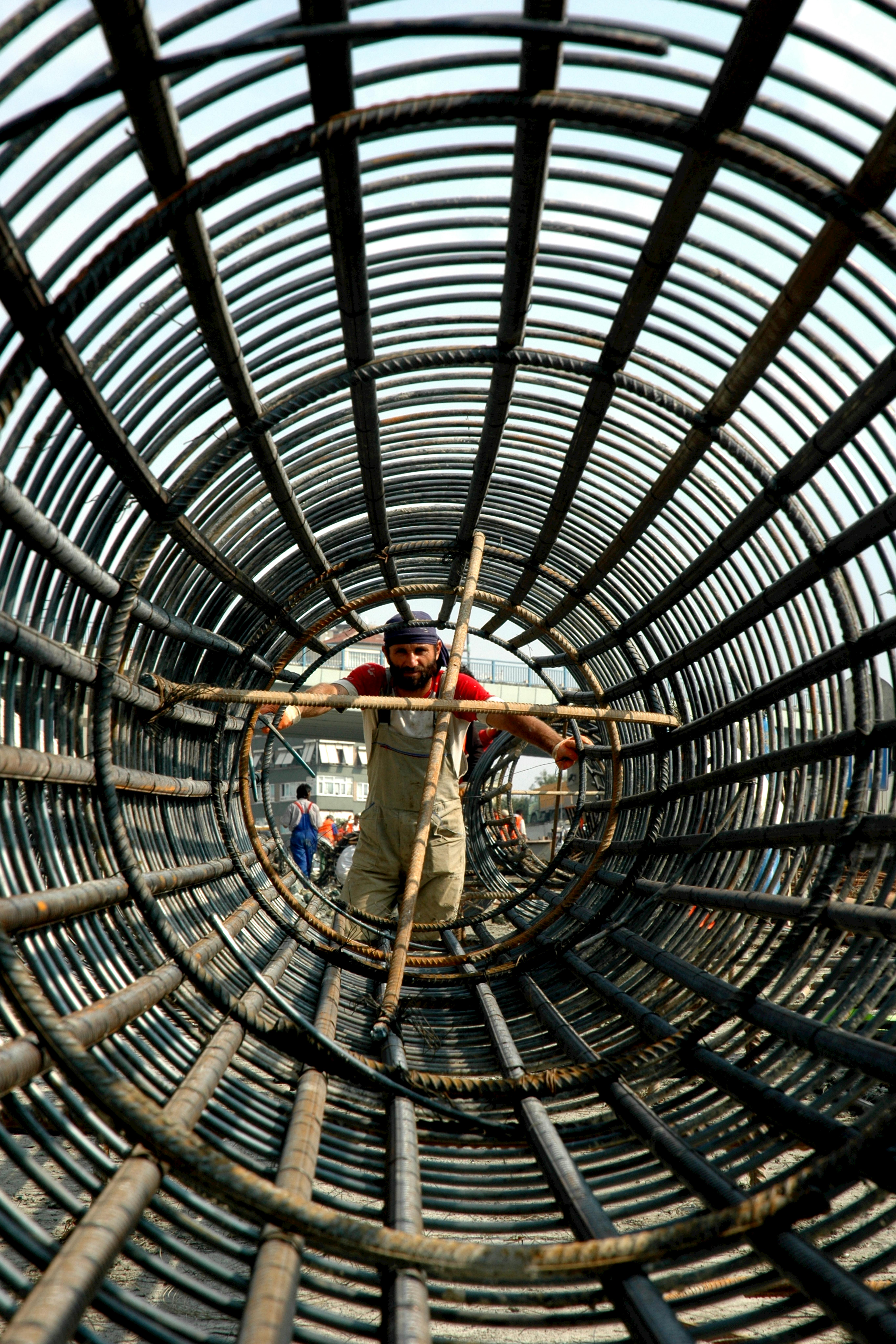 A construction worker navigating a steel framework tunnel, illustrating industrial craftsmanship.