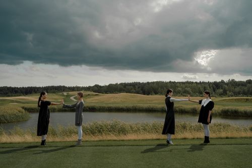 Free Four women maintaining social distance in a dramatic, cloudy outdoor setting. Stock Photo