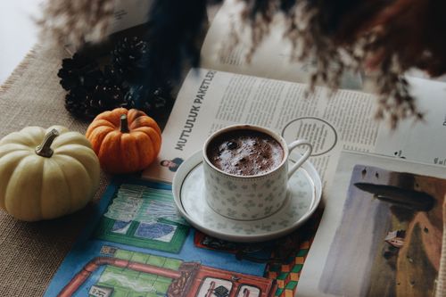 Free Cozy autumn scene with hot chocolate, pumpkins, and a magazine creating a warm atmosphere. Stock Photo