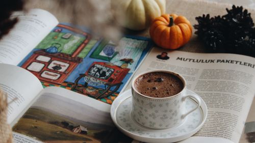 Free A warm mug of coffee with an open book and pumpkins creates a cozy autumn ambiance. Stock Photo