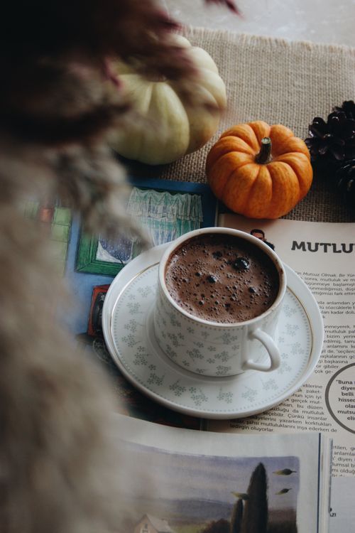 Free Warm autumn scene with a cup of hot cocoa, pumpkins, and magazine on a cozy table. Stock Photo